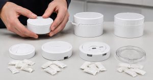 Packaging engineer comparing tamper-evident and child-resistant round cans with realistic slim caffeine pouches
